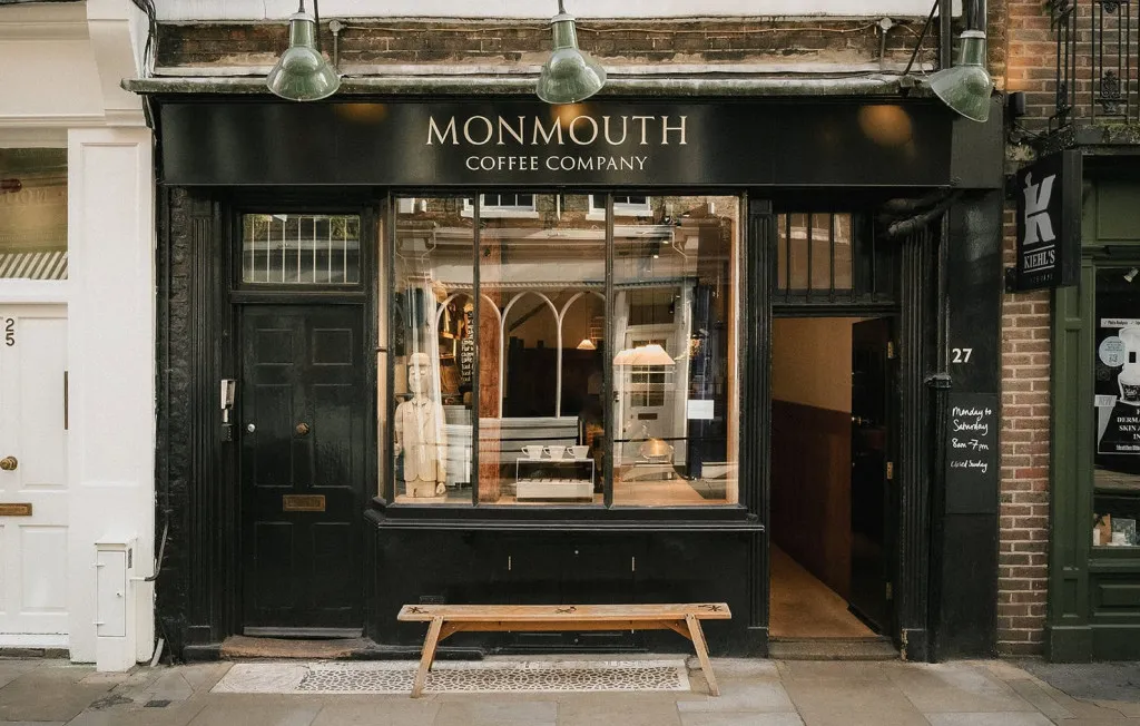 The green Monmouth Coffee shopfront in Covent Garden, with a bench beneath the window